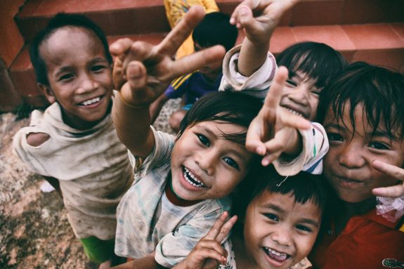 happy children with smiling faces making peace signs at the camera