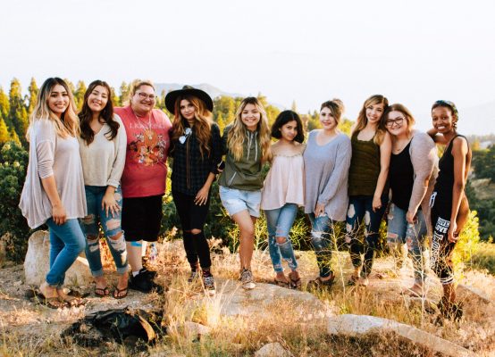 group of young women smiling and standing on a path in nature